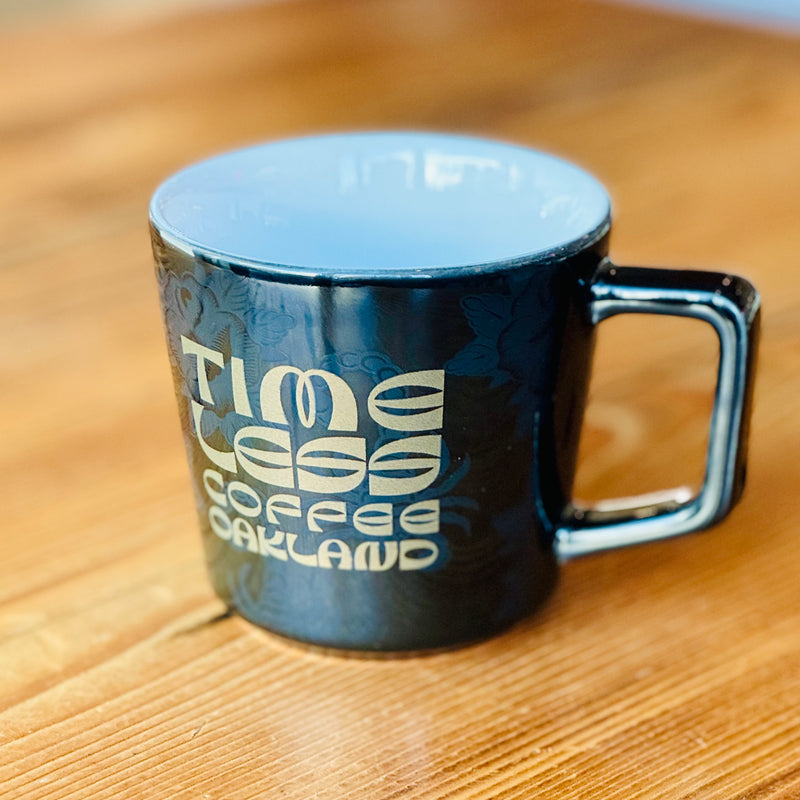 Timeless Coffee Roasters Black Diner Mug with Gold Writing on Wood Table